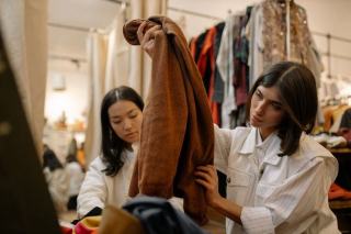 Portants de vêtements de seconde main triés par catégorie dans une friperie